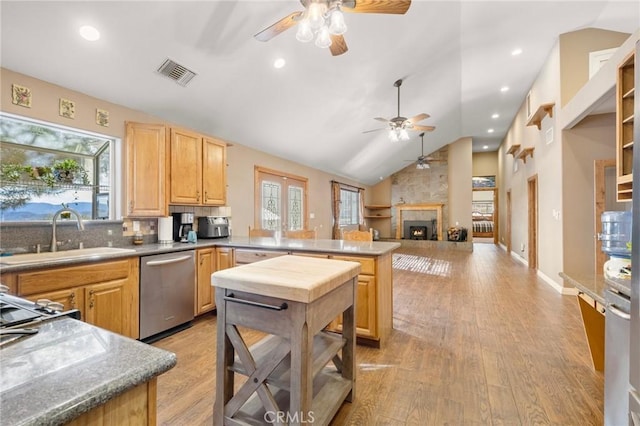 kitchen featuring visible vents, light brown cabinetry, a peninsula, stainless steel dishwasher, and a sink