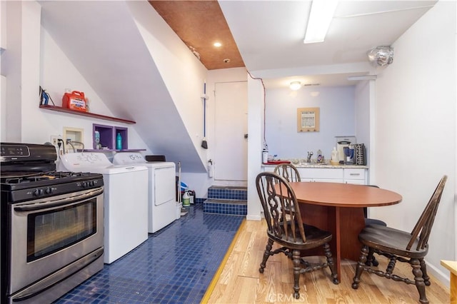 kitchen featuring white cabinets, wood-type flooring, separate washer and dryer, and stainless steel stove