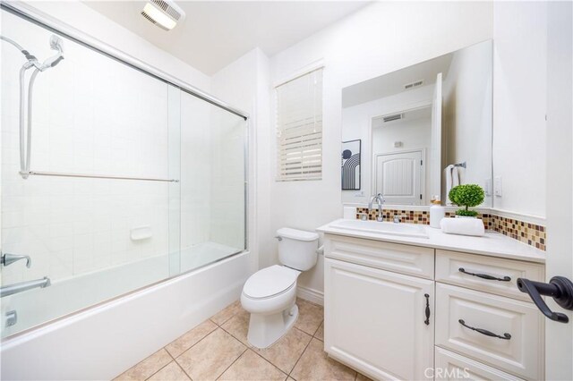 full bathroom featuring tasteful backsplash, vanity, toilet, tile patterned floors, and shower / bath combination with glass door