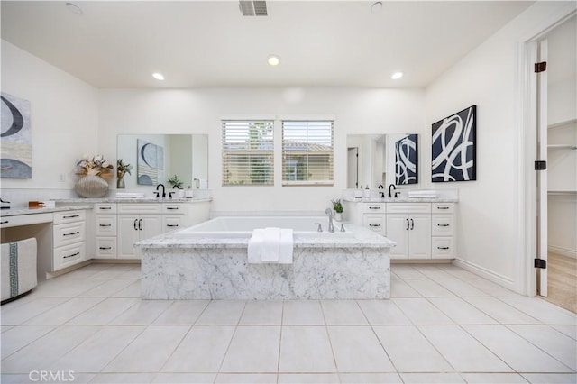 bathroom featuring vanity, tile patterned floors, and a relaxing tiled tub