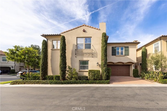 mediterranean / spanish house featuring a tiled roof, decorative driveway, and stucco siding