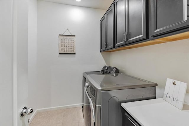 laundry room with cabinets, light tile patterned floors, and washing machine and clothes dryer