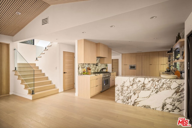 kitchen with light brown cabinetry, high end stove, and light wood-type flooring