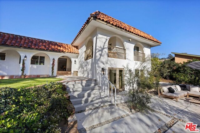 mediterranean / spanish home featuring an outdoor living space, a balcony, and a patio