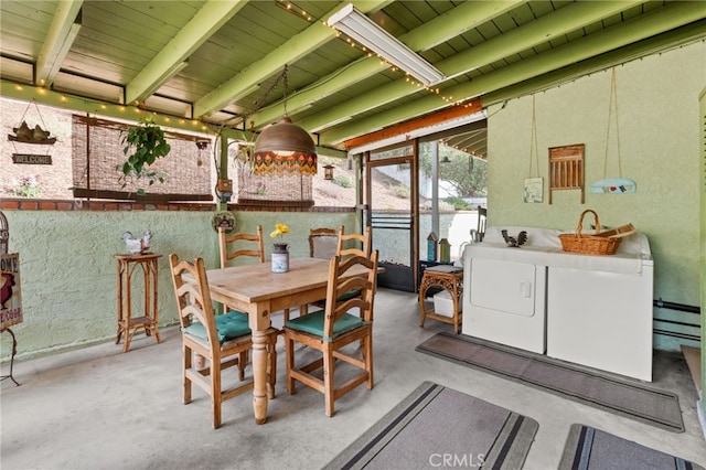 dining space featuring concrete flooring, beam ceiling, and washer and clothes dryer