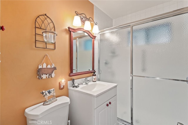 bathroom featuring a shower with shower door, toilet, and vanity