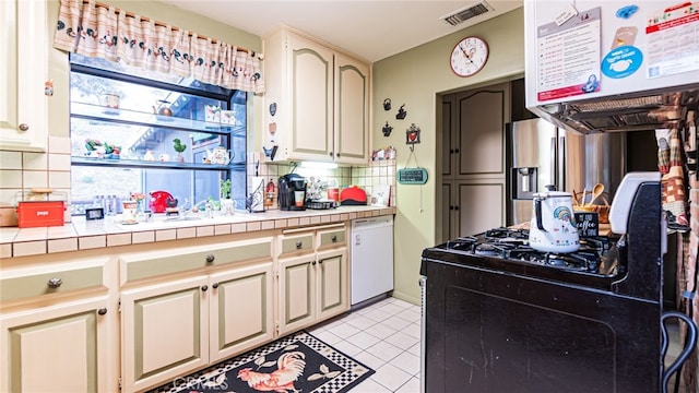 kitchen featuring tasteful backsplash, tile countertops, black gas stove, white dishwasher, and light tile patterned flooring