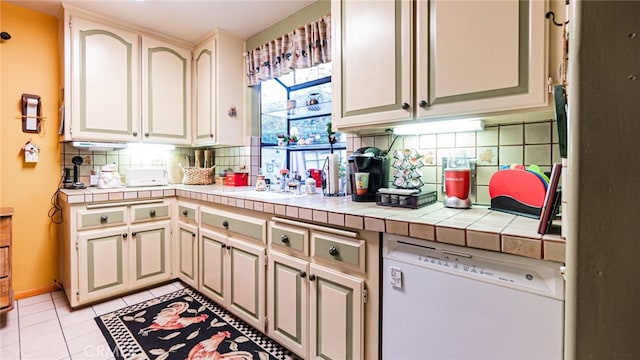 kitchen featuring light tile patterned floors, tile countertops, dishwasher, and backsplash