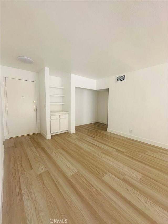 empty room featuring light wood-style floors, visible vents, and baseboards