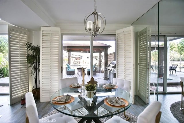 dining area with ornamental molding, a chandelier, and wood finished floors