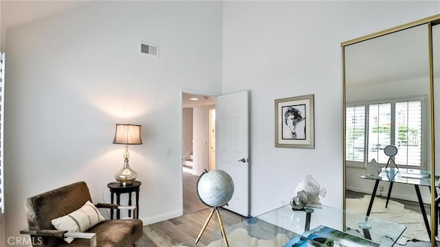 office featuring a towering ceiling, wood finished floors, visible vents, and baseboards