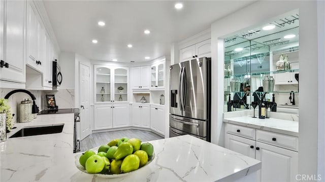 kitchen with recessed lighting, a sink, white cabinetry, stainless steel refrigerator with ice dispenser, and decorative backsplash