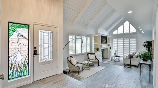 entryway featuring high vaulted ceiling, beam ceiling, a fireplace, and wood finished floors