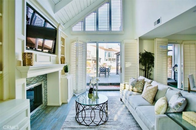 living room featuring high vaulted ceiling, visible vents, wood finished floors, and a glass covered fireplace