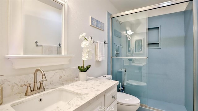 bathroom with toilet, a shower stall, and vanity