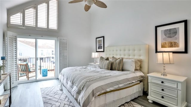 bedroom featuring a ceiling fan, access to outside, a towering ceiling, and wood finished floors