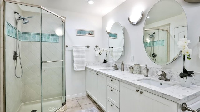 full bathroom featuring double vanity, a stall shower, tile patterned flooring, and a sink