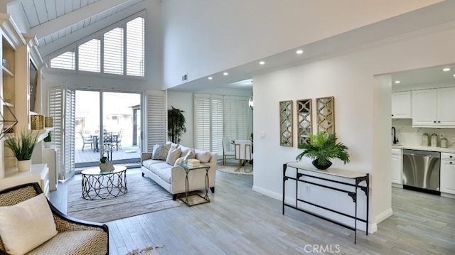 living area with visible vents, a towering ceiling, light wood-style flooring, and baseboards