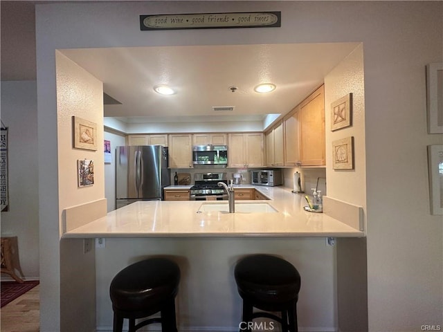 kitchen featuring a kitchen breakfast bar, appliances with stainless steel finishes, kitchen peninsula, and sink