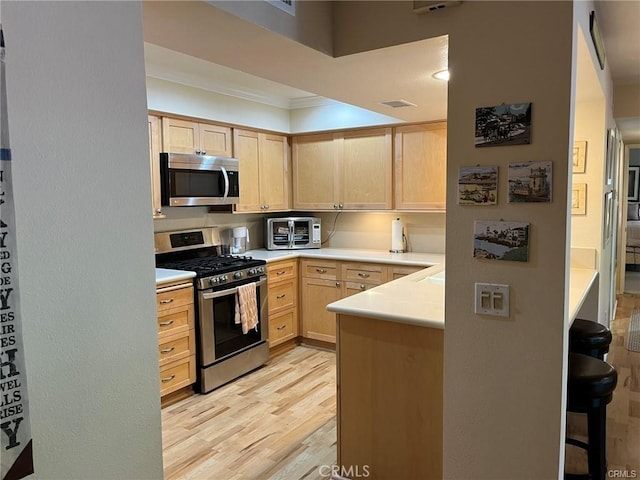 kitchen featuring ornamental molding, light brown cabinets, stainless steel appliances, and light hardwood / wood-style floors