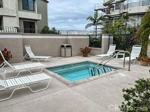 view of swimming pool featuring a hot tub and a patio