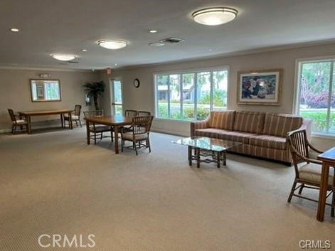 carpeted living room featuring crown molding and a healthy amount of sunlight