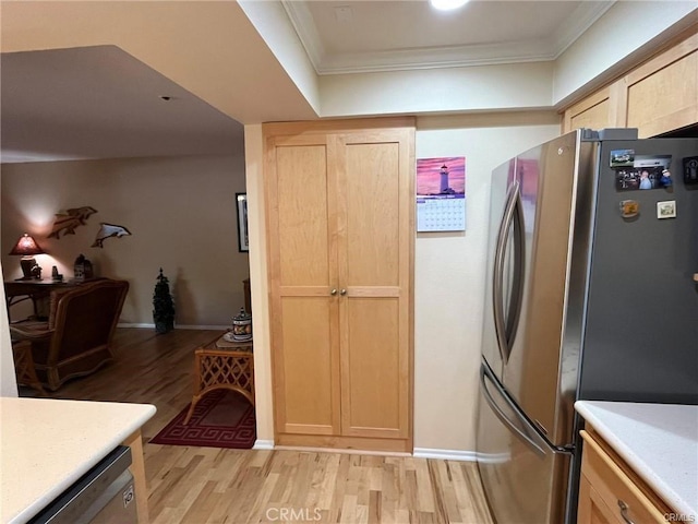 kitchen featuring crown molding, appliances with stainless steel finishes, light brown cabinetry, and light hardwood / wood-style flooring