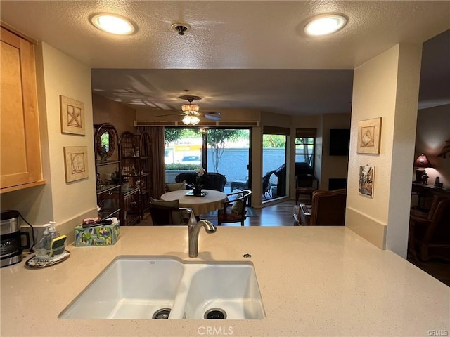 kitchen with a textured ceiling, ceiling fan, light brown cabinetry, and sink