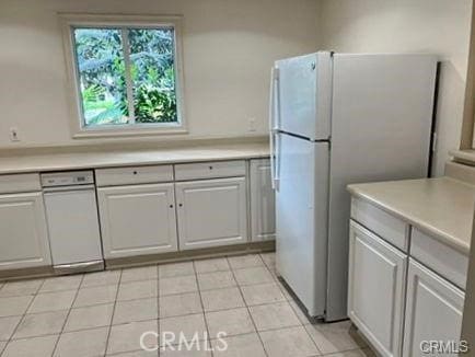 kitchen featuring light tile patterned floors, white refrigerator, and white cabinetry