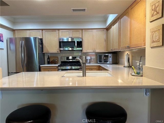 kitchen with a kitchen breakfast bar, crown molding, sink, and stainless steel appliances