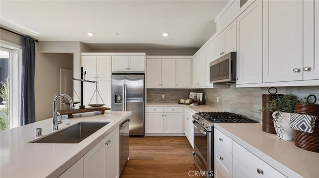 kitchen featuring white cabinets, appliances with stainless steel finishes, decorative backsplash, sink, and plenty of natural light