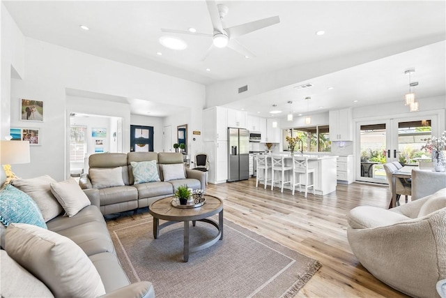 living room with ceiling fan, light hardwood / wood-style floors, and french doors