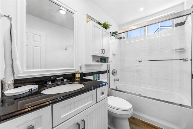 full bathroom featuring toilet, bath / shower combo with glass door, hardwood / wood-style flooring, and vanity