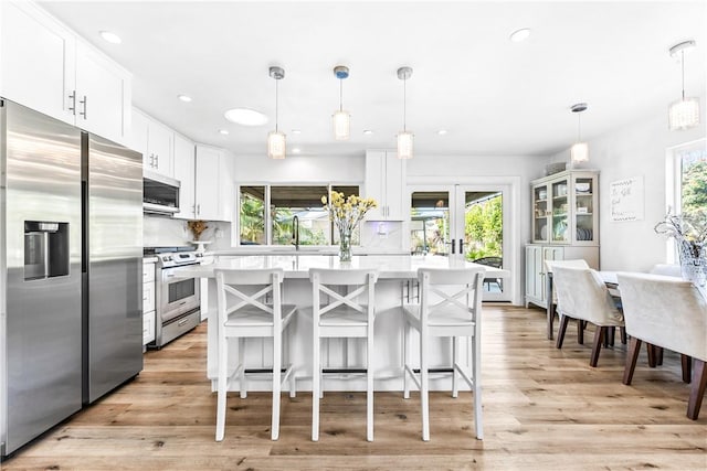 kitchen featuring a breakfast bar area, appliances with stainless steel finishes, pendant lighting, and white cabinetry