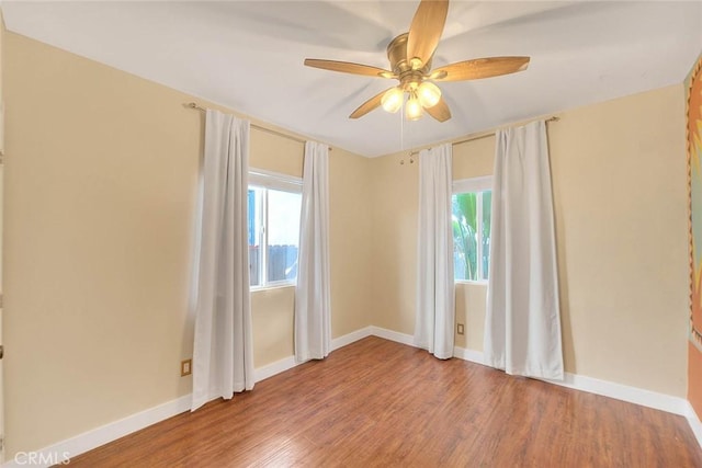 empty room featuring ceiling fan, a wealth of natural light, and hardwood / wood-style floors