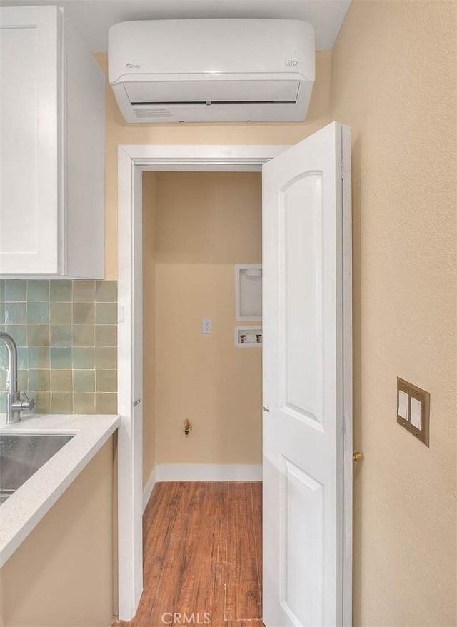 washroom featuring dark hardwood / wood-style flooring, sink, and a wall unit AC