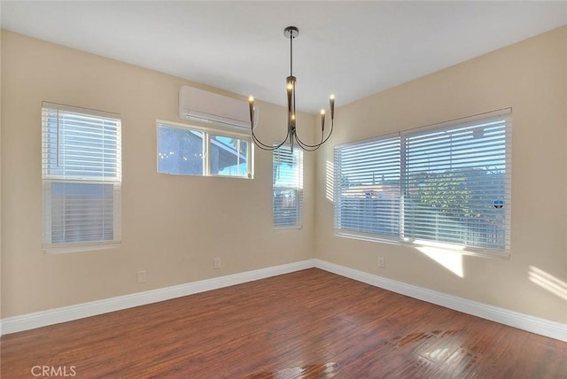 empty room featuring a chandelier, a wall mounted AC, and hardwood / wood-style flooring