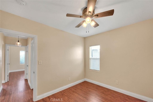 empty room with ceiling fan, a wealth of natural light, and hardwood / wood-style flooring