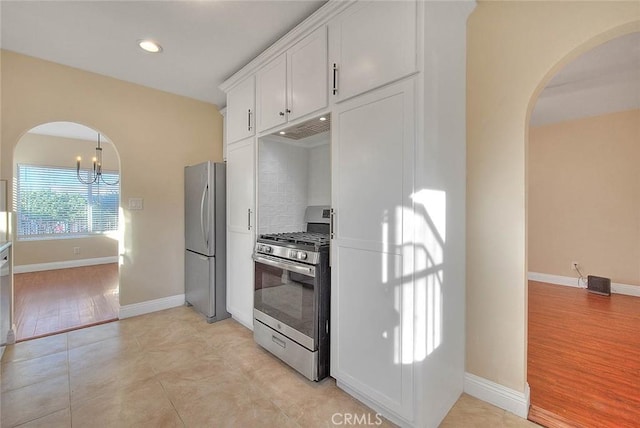 kitchen with light tile patterned floors, stainless steel appliances, a chandelier, and white cabinetry