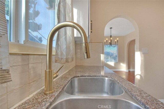 details featuring stone countertops, sink, hanging light fixtures, and a notable chandelier