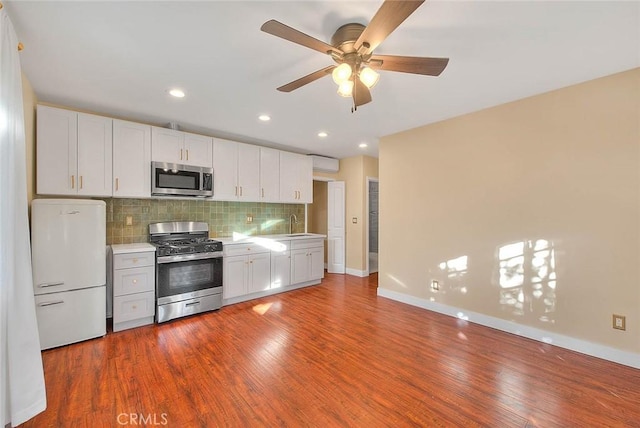 kitchen with hardwood / wood-style flooring, stainless steel appliances, decorative backsplash, and white cabinets