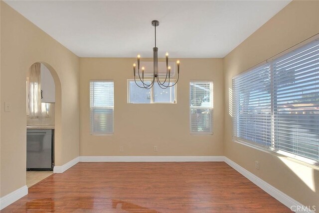 unfurnished dining area with hardwood / wood-style flooring and a notable chandelier