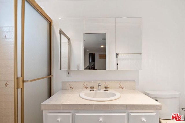 bathroom with a shower with shower door and vanity