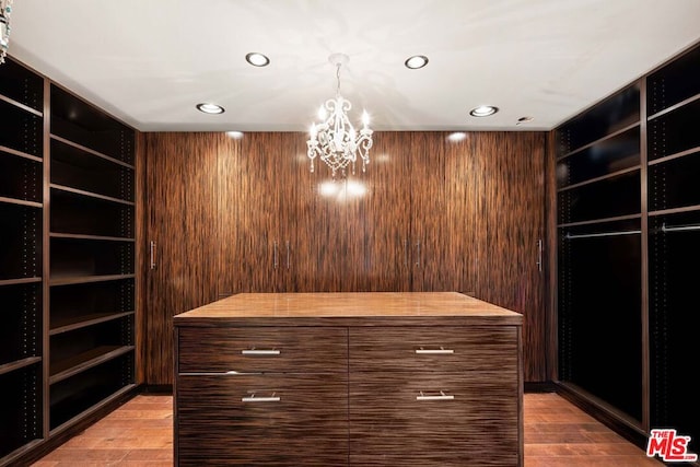 spacious closet featuring an inviting chandelier and light hardwood / wood-style flooring