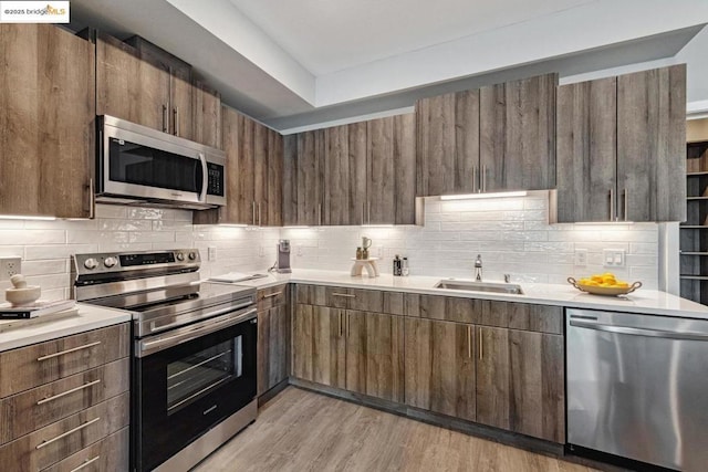 kitchen featuring light hardwood / wood-style floors, sink, backsplash, and appliances with stainless steel finishes