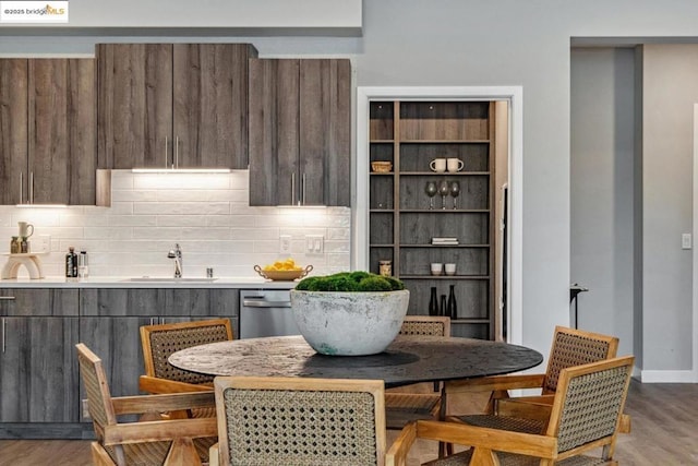 kitchen with stainless steel dishwasher, sink, tasteful backsplash, and light hardwood / wood-style flooring