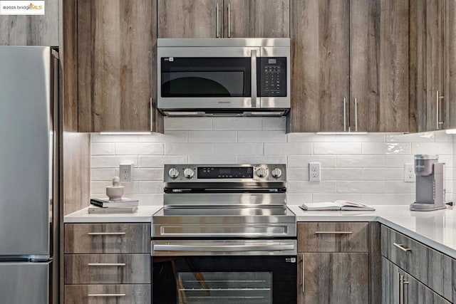 kitchen featuring stainless steel appliances, dark brown cabinets, and backsplash