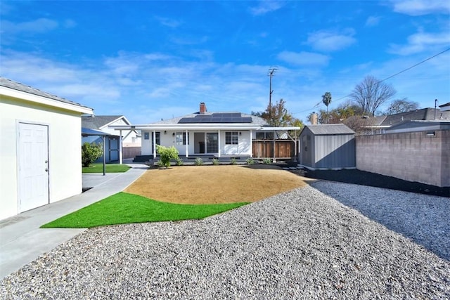 rear view of property with a lawn, a shed, and solar panels