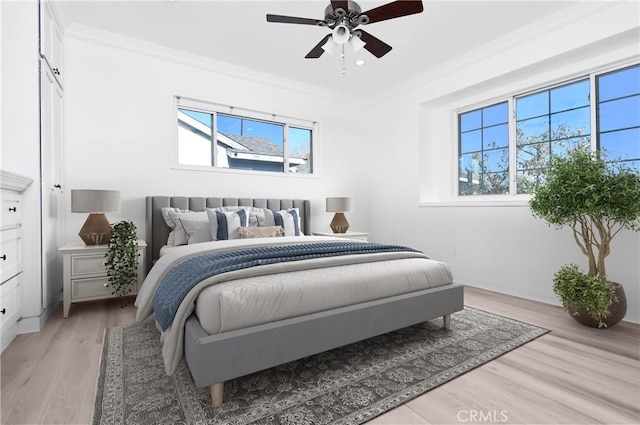 bedroom with ceiling fan, multiple windows, crown molding, and light wood-type flooring