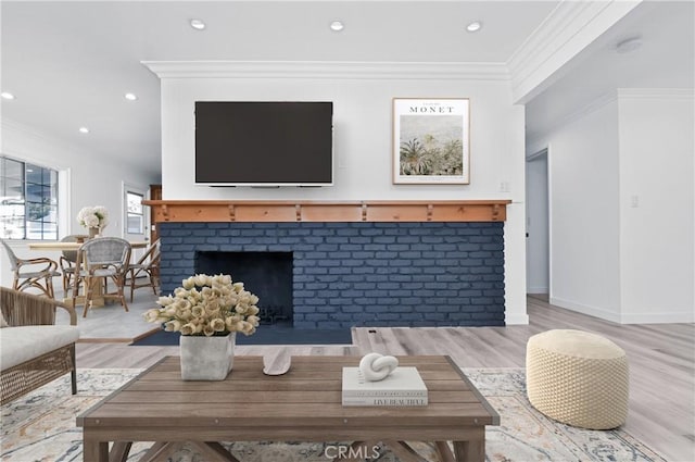 living room with a fireplace, crown molding, and light hardwood / wood-style flooring